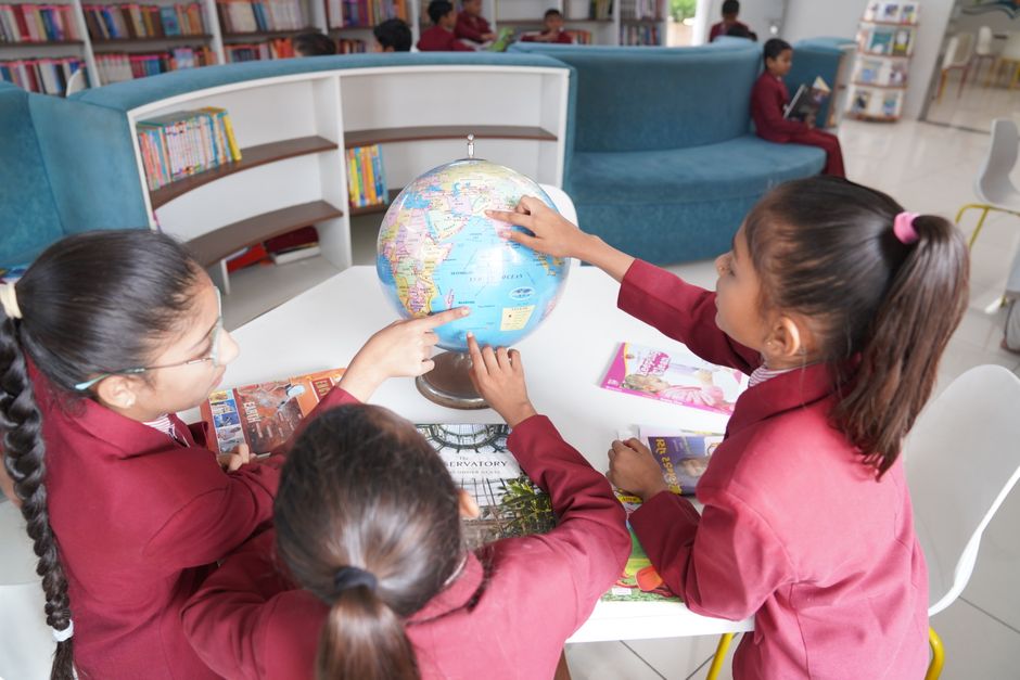 Children learning together with a globe in a library.